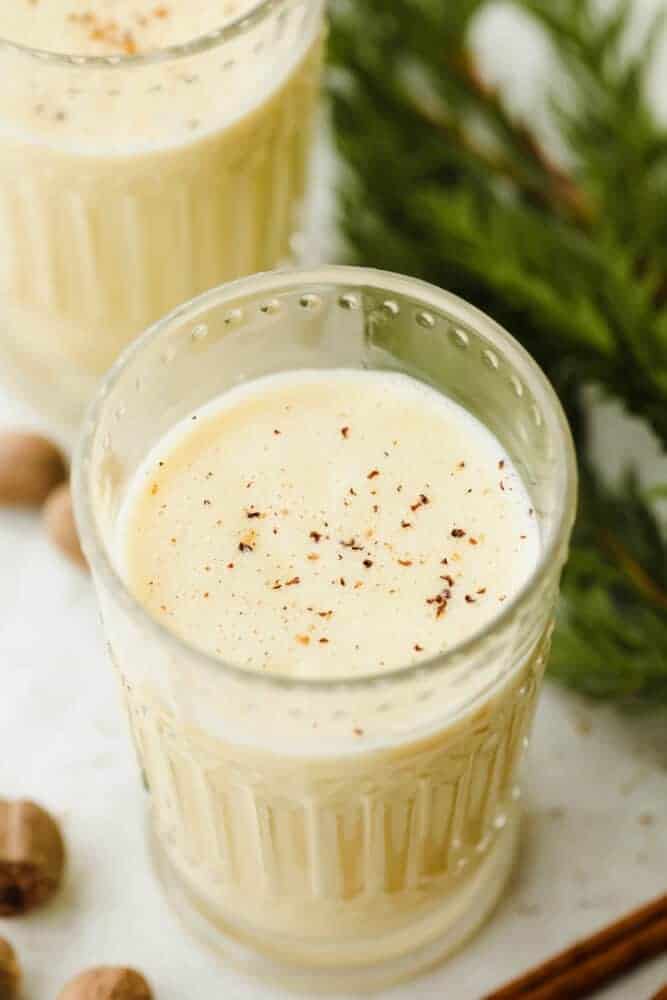Nonalcoholic eggnog is incredibly easy to make and such a delight for the entire family for the holiday season. If you have milk, cream, sugar, and eggs, you can have this eggnog ready in 20 minutes! Eggnog in a glass garnished with nutmeg.