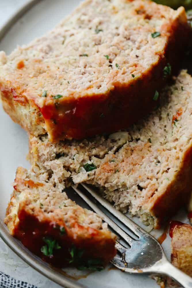 This tasty turkey meatloaf is light and lean but filled with so much flavor! Each bite is perfectly seasoned and tender, you'll love it! Breaking off a piece of meatloaf with a fork.