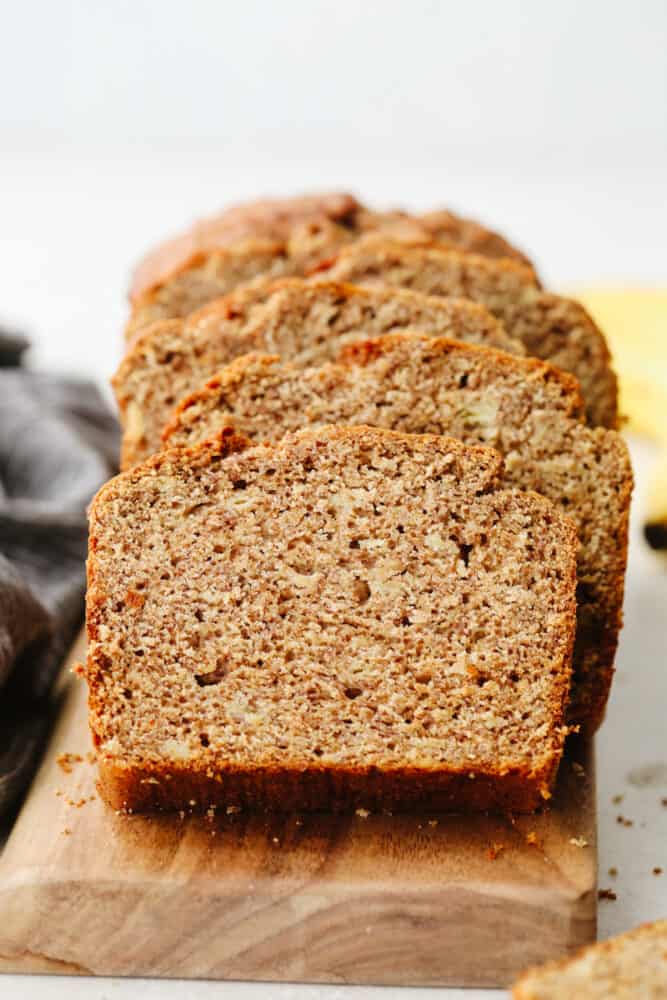 This healthy banana bread is made with NO sugar and it tastes absolutely divine! After you bake up this delicious bread the serve yourself up a slice or two, It's SOO GOOD. Banana bread sliced up on a wooden cutting board.