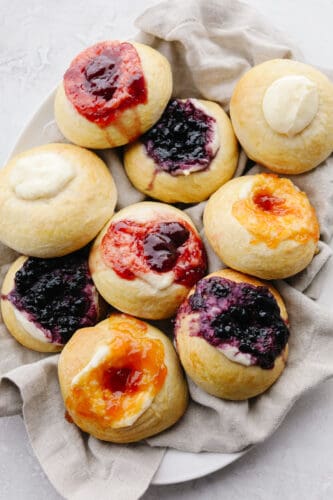 These delicious dough-filled, buttery soft kolaches pack a punch of flavor. This recipe is a tried and true favorite that will be a hit with your entire family! Different flavored kolaches on a platter.