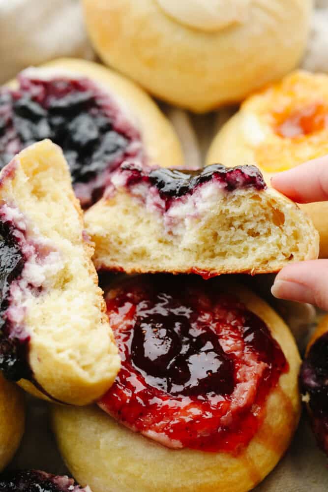 These delicious dough-filled, buttery soft kolaches pack a punch of flavor. This recipe is a tried and true favorite that will be a hit with your entire family! A kolache broken apart and ready to eat.