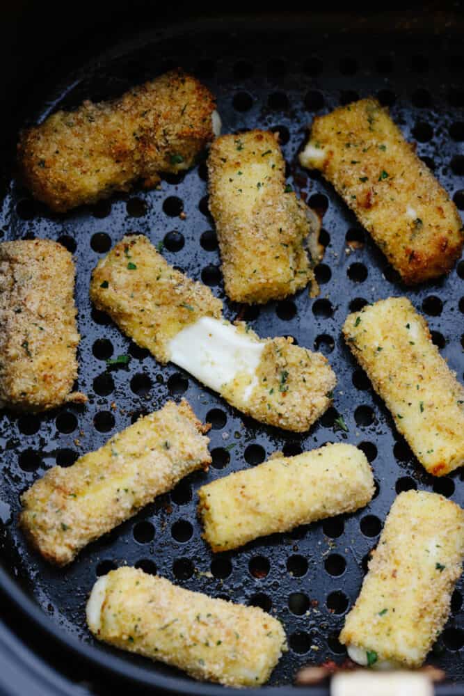 Crispy, cheesy, and delicious, these easy air fryer mozzarella sticks are going to be your new favorite snack! They're super simple to prepare and cook up in less than 10 minutes! Mozzarella sticks in an air fryer basket.