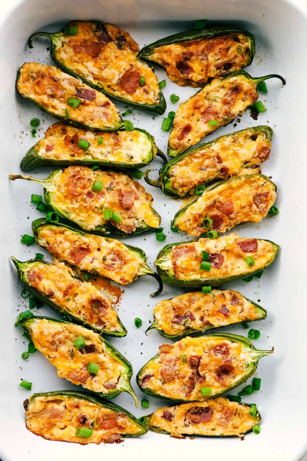 These jalapeño poppers are filled with a cream cheese mixture, topped with crumbled bacon pieces, and then baked to perfection. You won't be able to stop at one! Jalapeño poppers being baked.