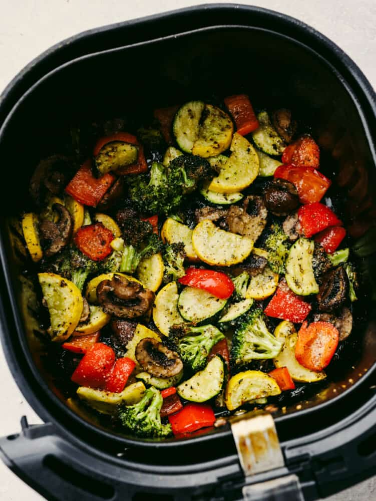 Cooking your vegetables in an air fryer doesn't get much easier (or more delicious!) than this! Crispy and tender, these veggies will be the best side dish that you've ever had! Vegetables being cooked in an air fryer.