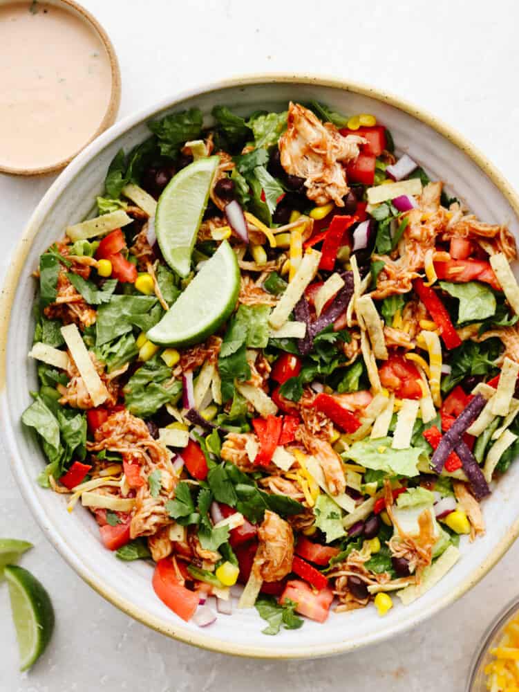 This BBQ chicken salad is healthy and packed to the brim with flavor! Filled with veggies, shredded chicken, and crispy tortilla chips, this salad really takes off when you add in the dressing. It's to die for! A bowl of BBQ chicken salad.