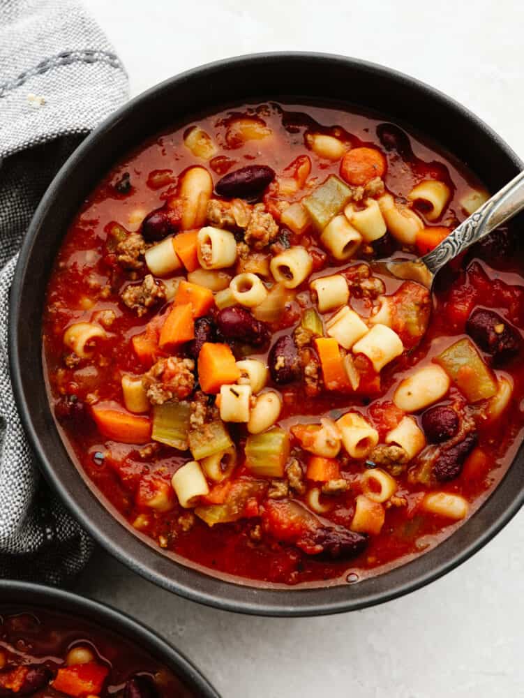 Slow cooker Pasta e Fagioli soup is a rich and hearty Italian soup loaded with pasta, vegetables, beans, and lean ground beef. It's hearty, comforting, and oh so delicious! A bowl of pasta e fagioli with a silver spoon.