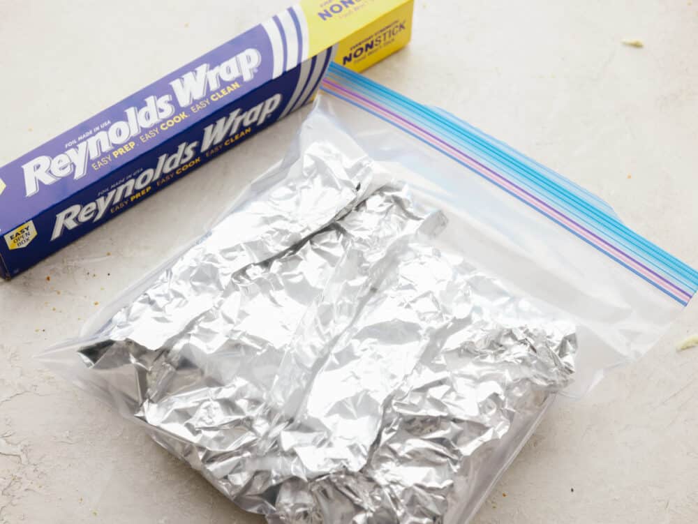 These foil french bread pizzas made with Reynolds Wrap® Non-Stick Foil are perfect for any family dinner! Crispy, cheesy, and delicious, your family won't be able to resist coming back for seconds! Pizza being wrapped in foil and stored in a freezer bag to store.