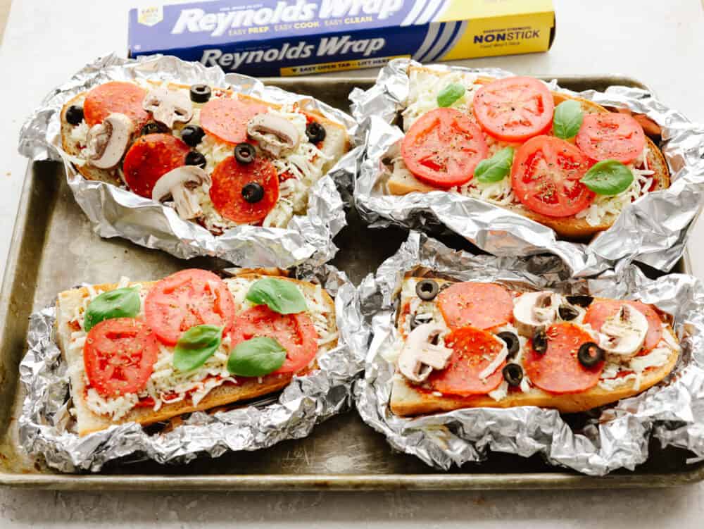 These foil french bread pizzas made with Reynolds Wrap® Non-Stick Foil are perfect for any family dinner! Crispy, cheesy, and delicious, your family won't be able to resist coming back for seconds! Foil french bread pizzas cooked and ready to eat.