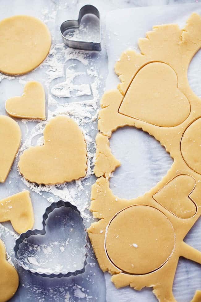 You cannot beat homemade sugar cookies with a crisp edge and a soft center. These are the BEST! Topped with my favorite cream cheese frosting and sprinkles, these sugar cookies are a tried and true favorite. A picture showing how to cut out shapes in the dough.