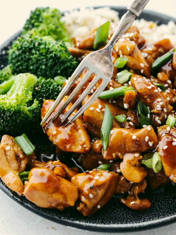 This teriyaki chicken will be the best that you ever make! The tender, juicy chicken is coated with the most amazingly flavored sauce. Once you eat this, it will become your new favorite! A close up of a teriyaki chicken bowl with a fork in a piece of chicken.