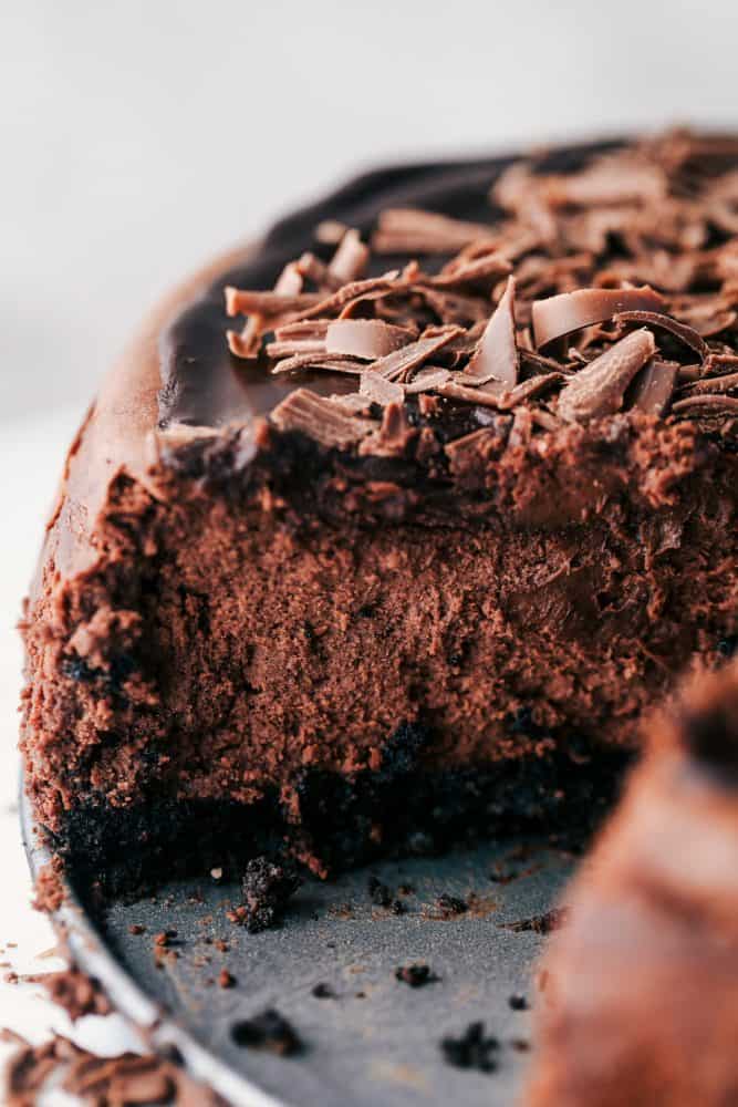 Death by chocolate cheesecake has an Oreo crust with creamy, decadent, and rich chocolate cheesecake. Topped with chocolate ganache, this is a chocolate lover's dream come true! A slice removed of Death by Chocolate Cheesecake.
