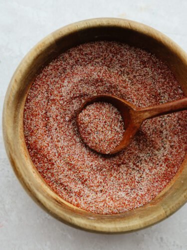 This recipe for homemade seasoning salt will have you making this from scratch and never buying it at the store again! It has the perfect amount of flavor that is ideal for adding to any dish! Seasoning salt in a wooden bowl being dished with a wooden spoon.