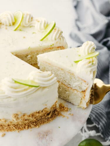This moist key lime cake with cream cheese frosting is the perfect blend of tangy and sweet! You won't be able to stop at one slice! Taking a slice of key lime cake with a cake server.