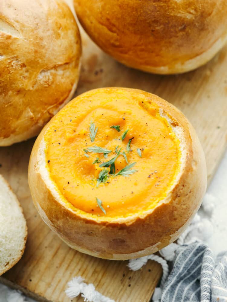 Homemade bread bowls are a simple and delicious way to take all of your soups to the next level! These bread bowls are perfectly crisp on the outside and soft and airy on the inside. A bread bowl filled with carrot soup.
