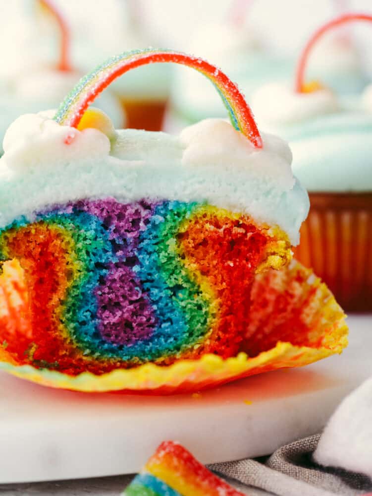 No need for a pot of gold when you’ve got these cupcakes around! These colorful rainbow cupcakes are perfectly moist, topped with the most amazing buttercream. They’ll light up any party! Closeup of a cupcake cut in half.