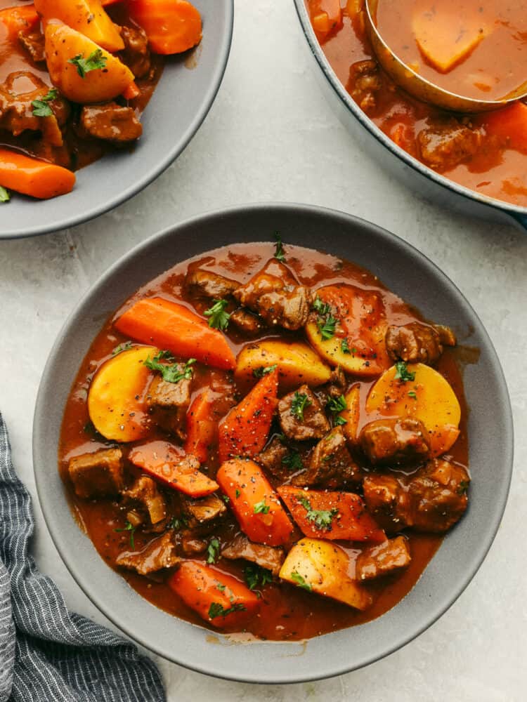 Your family is going to love this hearty Guinness beef stew! This traditional Irish meal is filled with rich, meaty flavor, tender vegetables, and melt-in-your-mouth beef! Irish Guinness Stew in a gray stoneware bowl.