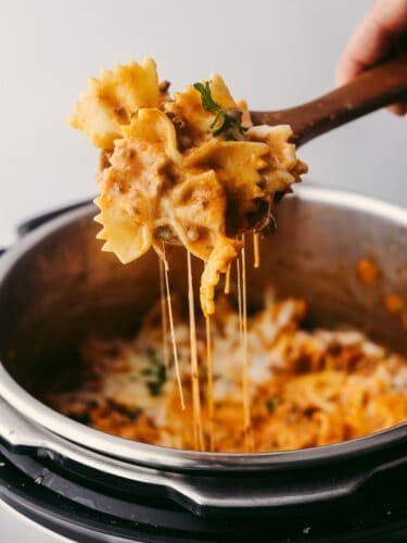 This Instant Pot recipe is filled with all the lasagna flavors you love! Layers of creamy ricotta, melty mozzarella, and ground beef seasoned with Italian herbs come together in this super easy dish! Scooping Instant Pot lasagna with a wooden spoon.
