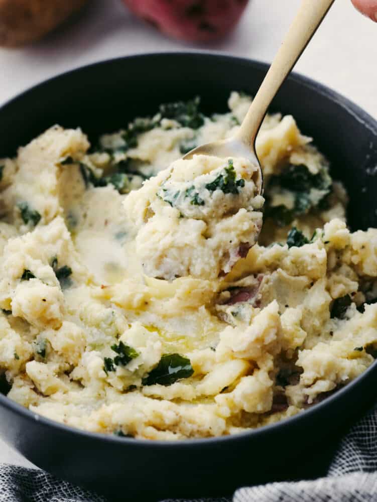 Creamy, buttery, and full of flavor, these Colcannon potatoes will become your new go-to side dish recipe for any meal! They are simple and easy to make and packed with all kinds of delicious ingredients! A close up of a spoon scooping colcannon out of a bowl.