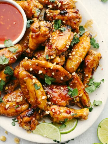 These Thai glazed chicken wings have a delicious sauce with a twist! Perfect for any party, game day, or get-together, these wings are the perfect appetizer! A plate of Thai glazed chicken wings garnished with cilantro.