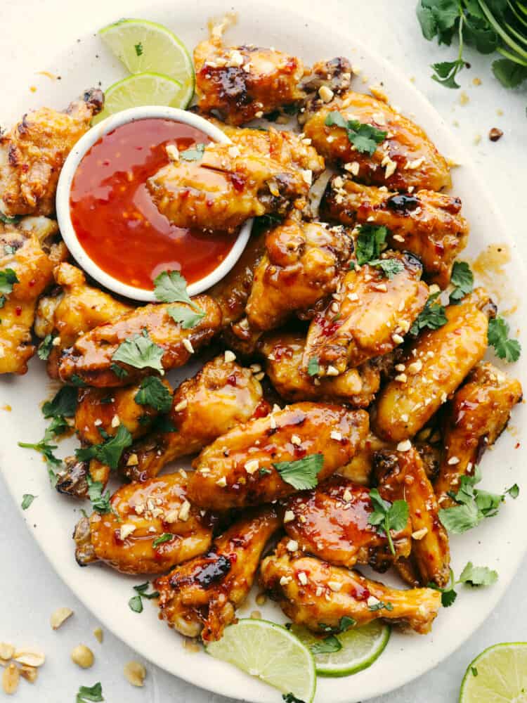 These Thai glazed chicken wings have a delicious sauce with a twist! Perfect for any party, game day, or get-together, these wings are the perfect appetizer! A platter of wings with a small bowl of Thai sauce.