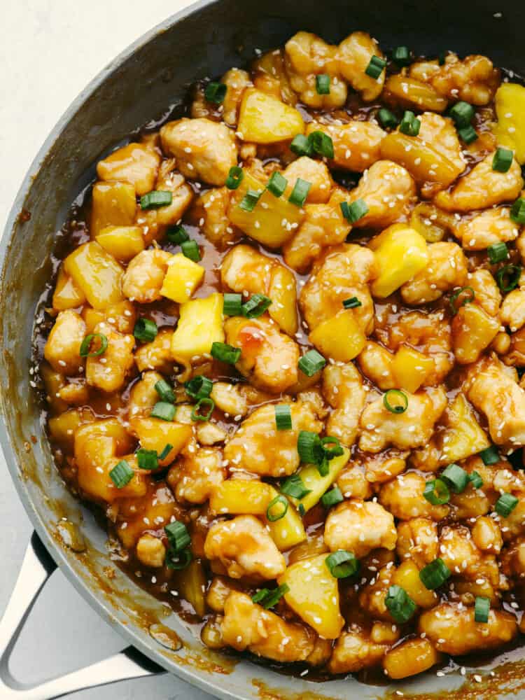 This crispy, saucy chicken is every pineapple lover's dream! Pineapple chicken is the best mix of sweet and savory. It's a quick and easy dinner that your family will go crazy over! Pineapple chicken simmering in a pan.