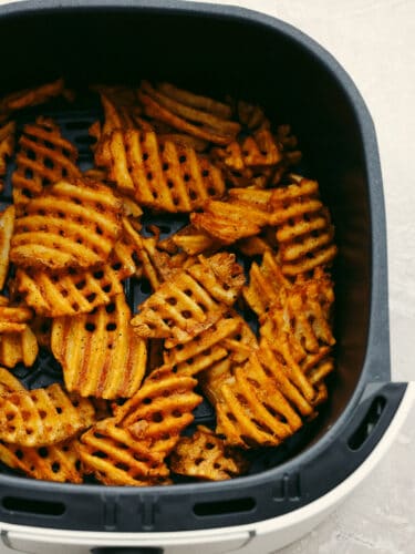 These air fryer frozen waffle fries are so easy and make the perfect side to any meal! Crispy and flavored to perfection, they will leave your mouth watering and wanting more! Waffle fries in an air fryer basket.