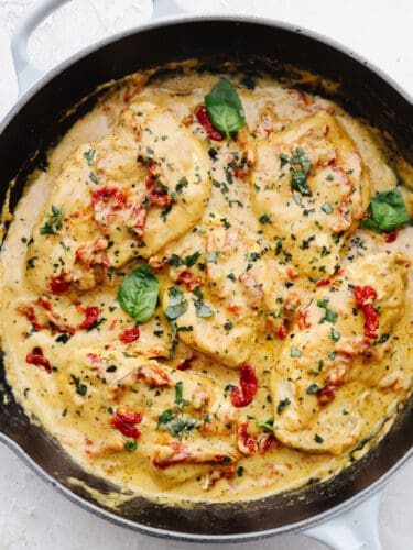 Marry me chicken is juicy and flavorful and smothered in a creamy parmesan sauce. Seasoned with savory herbs and sun-dried tomatoes, this dish will melt in your mouth, and will leave you begging for a proposal! A skillet with marry me chicken cooked and ready to eat.