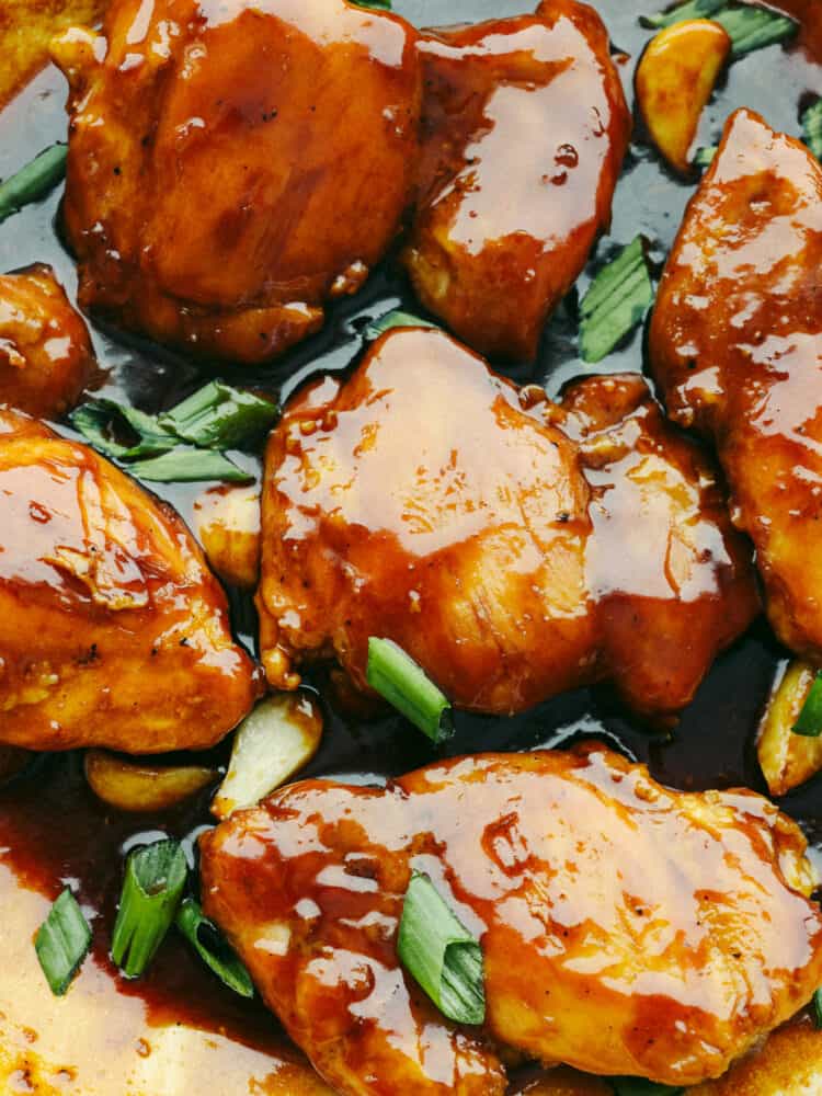 Caramel chicken is an amazing 30-minute meal that you won't be able to get enough of! The chicken is glazed in the best sweet and tangy Asian sauce and is even picky eater-approved! Closeup of chicken covered in caramelized Asian sauce.