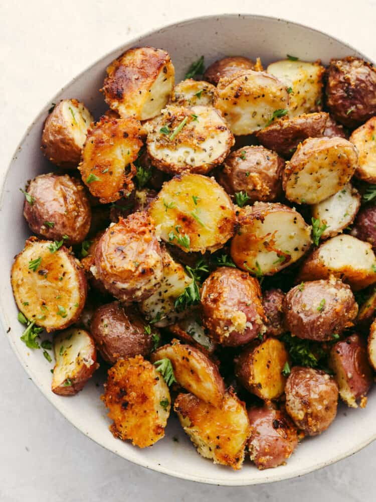 Parmesan garlic roasted potatoes have a crispy edge and tender center. Their mouthwatering parmesan garlic flavor makes them the perfect side! Parmesan garlic potatoes in a white bowl.