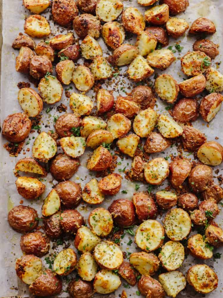Parmesan garlic roasted potatoes have a crispy edge and tender center. Their mouthwatering parmesan garlic flavor makes them the perfect side! Roasted parmesan garlic potatoes on a baking sheet.
