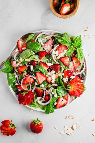 Strawberry spinach salad is a perfect combination of fresh spinach, juicy strawberries, crunchy onions, and soft feta cheese; all tossed together with a creamy poppyseed dressing! All the flavor, texture, and deliciousness in one bowl! A plate of strawberry spinach salad.