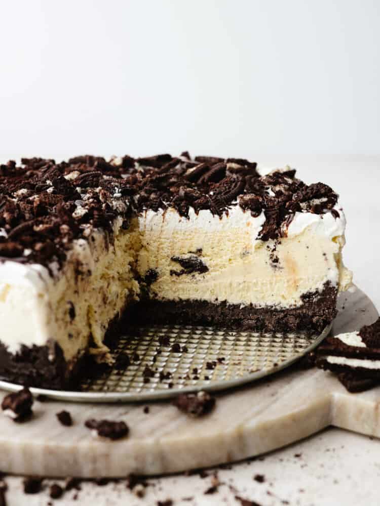 Ice cream cake is the best of both worlds...ice cream in the form of a cake! This cookies and cream ice cream cake is exploding with layers of oreo cookies, ice cream, and gooey fudge sauce. The side view of a cookies and cream ice cream cake with a slice taken out so that you can see the inside.