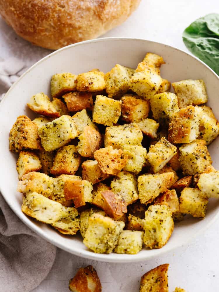 These quick and easy air fryer croutons will give your salads and recipes that "wow" factor! A fresh loaf of bread cubed, seasoned, and air fried to perfection. Seasoned croutons in a white bowl.