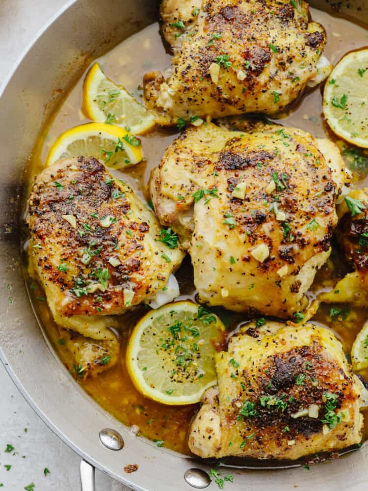 Juicy chicken is coated in lemon pepper seasoning and baked to tender perfection in this easy recipe. The brown butter garlic lemon sauce on top is absolutely incredible! Closeup of brown butter lemon pepper chicken in a metal skillet.