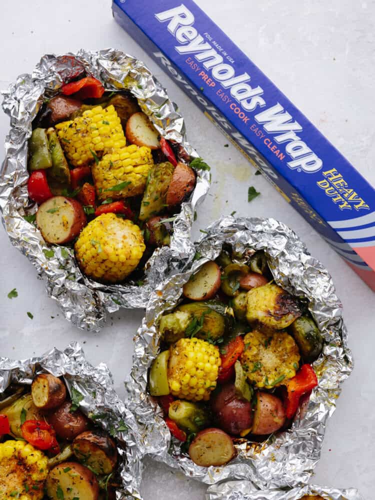 These foil pack grilled vegetables made with Reynolds Wrap® Heavy Foil are perfect for BBQ season! They cook just right on your grill and come out tender and seasoned to perfection. This is one side dish that you don't want to miss! Top view of 2 Reynolds vegetable packs with a box of Reynold foil on the right.