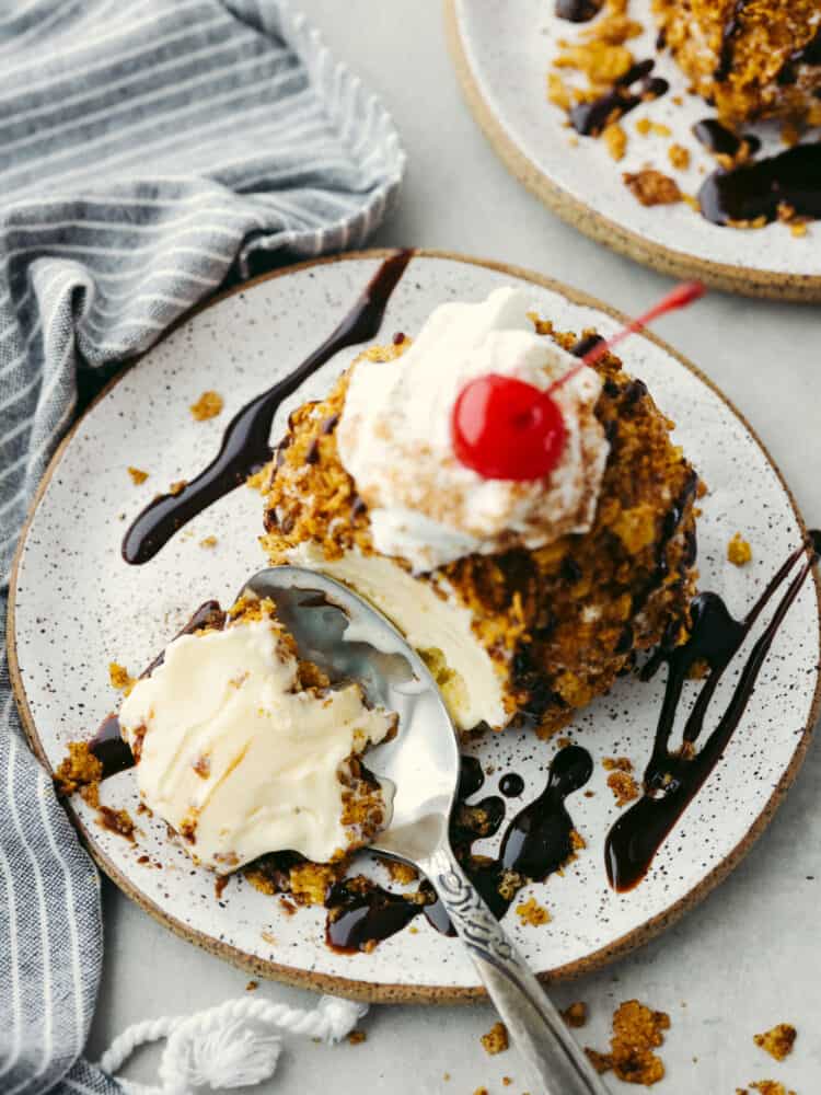 Get your sweet tooth ready, this fried ice cream recipe is the perfect combination of crispy and creamy! Vanilla ice cream is coated with buttery cinnamon sugar cornflakes for a texture your tastebuds will go crazy over! Top-down view of a bite being taken out of fried ice cream with a silver spoon.