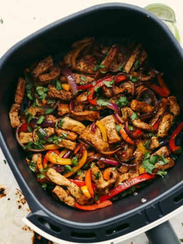 Celebrate with these insanely delicious and easy air fryer pork fajitas! They are restaurant-quality fajitas in the comfort of your own home, and your entire family will go crazy over them! Cooked pork, pepper and onions seasoned in fajita seasoning and in an air fryer basket.