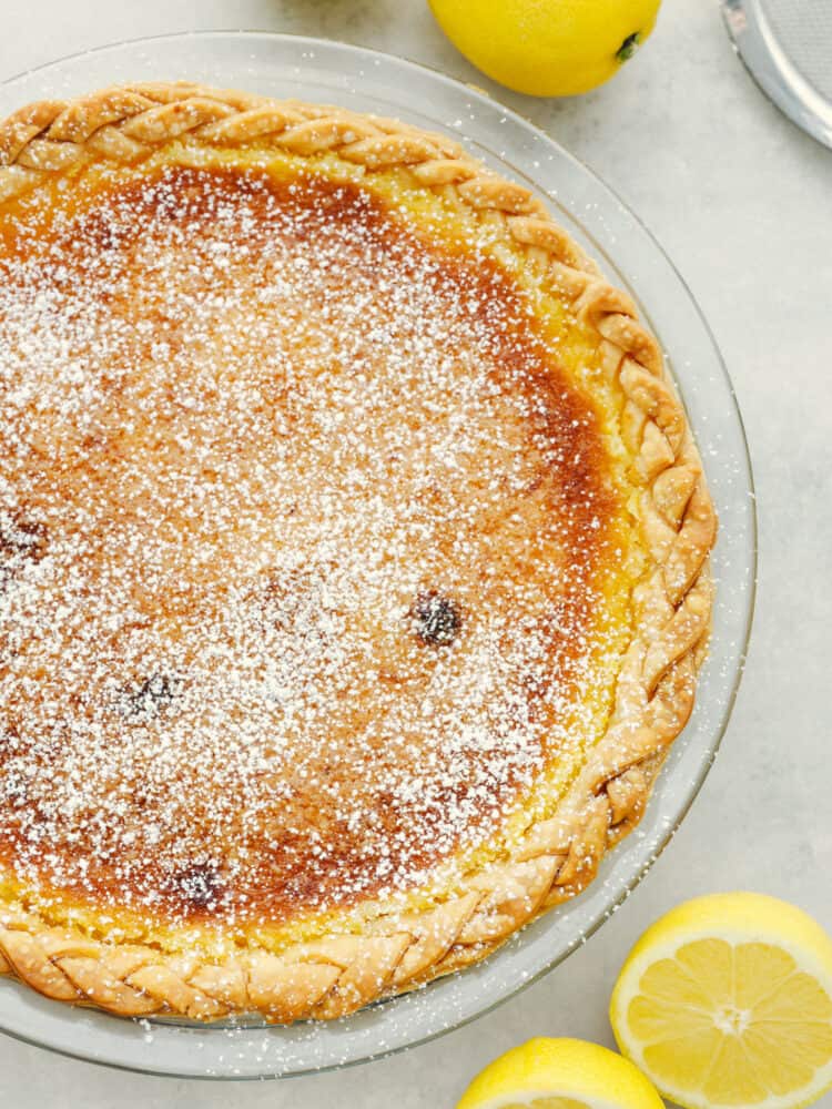 This lemon chess pie is packed purely with lemon filling and is a lemon-lovers dream come true! The texture is smooth and creamy with a deliciously flakey crust that just about anyone will go crazy for! The top view of a lemon chess lie sprinkled with powdered sugar.