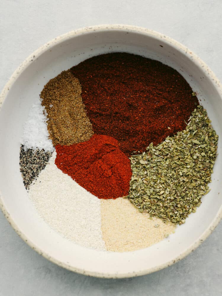 This homemade chili seasoning is filled with all the best herbs and spices to elevate your meal! Once you make your own delicious blend, you won't want storebought again! Top-down view of chili seasoning ingredients added to a stoneware bowl.