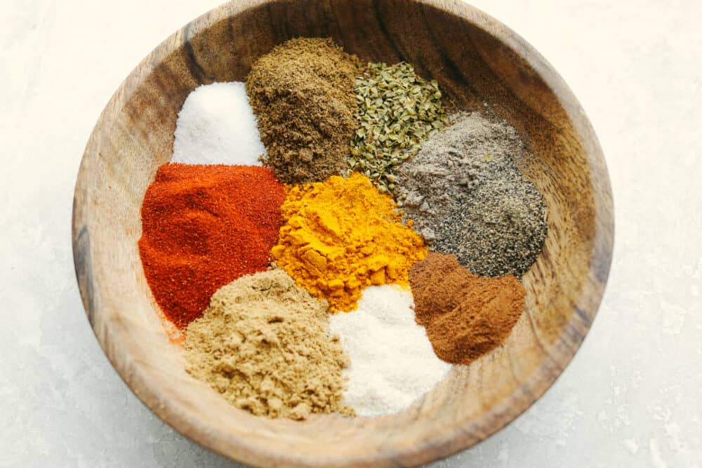 Shawarma seasoning brings aromatic and authentic Middle Eastern flavors to your recipes. This easy to assemble spice blend is great to make ahead and have on hand when you want to elevate your cooking flavors. A wooded bowl filled with individual spices that haven't been mixed together yet.