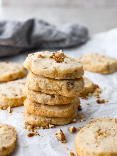 These pecan shortbread cookies are insanely delicious! They melt in your mouth with their fall-apart texture and sweet taste. The added texture of a crunchy pecan makes these practically perfect! A stack of pecan shortbread cookies.