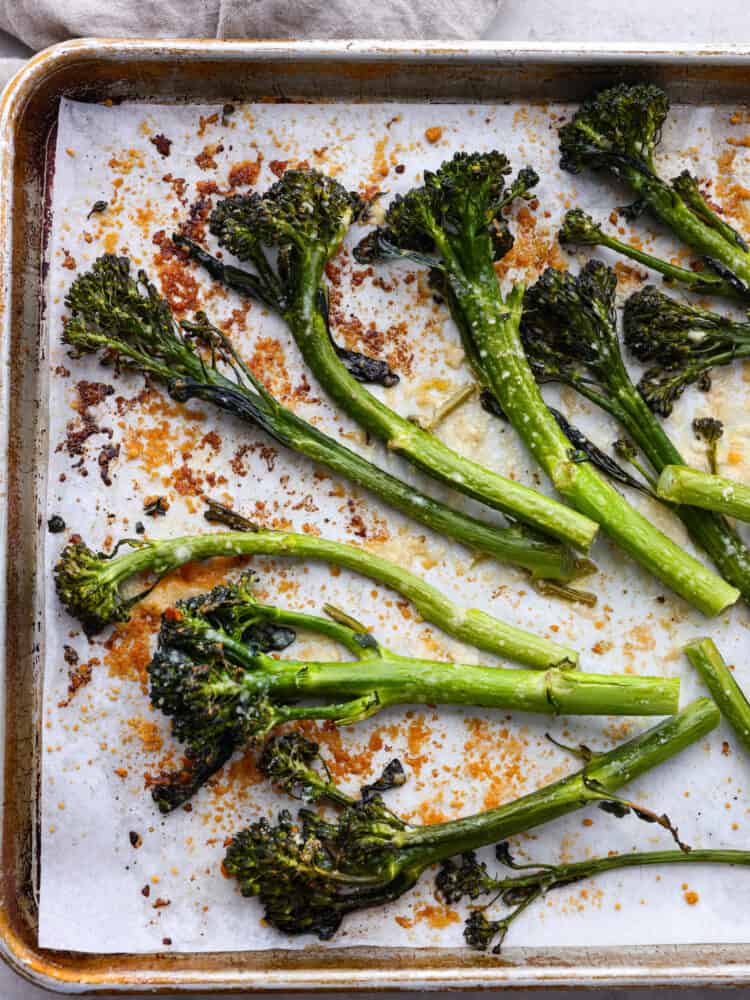 If you are looking for the perfect side dish that pairs well with everything, this lemon garlic broccolini is it! It's seasoned with delicious flavors and roasted to perfection! Roasted broccolini on a baking sheet with parchment paper.