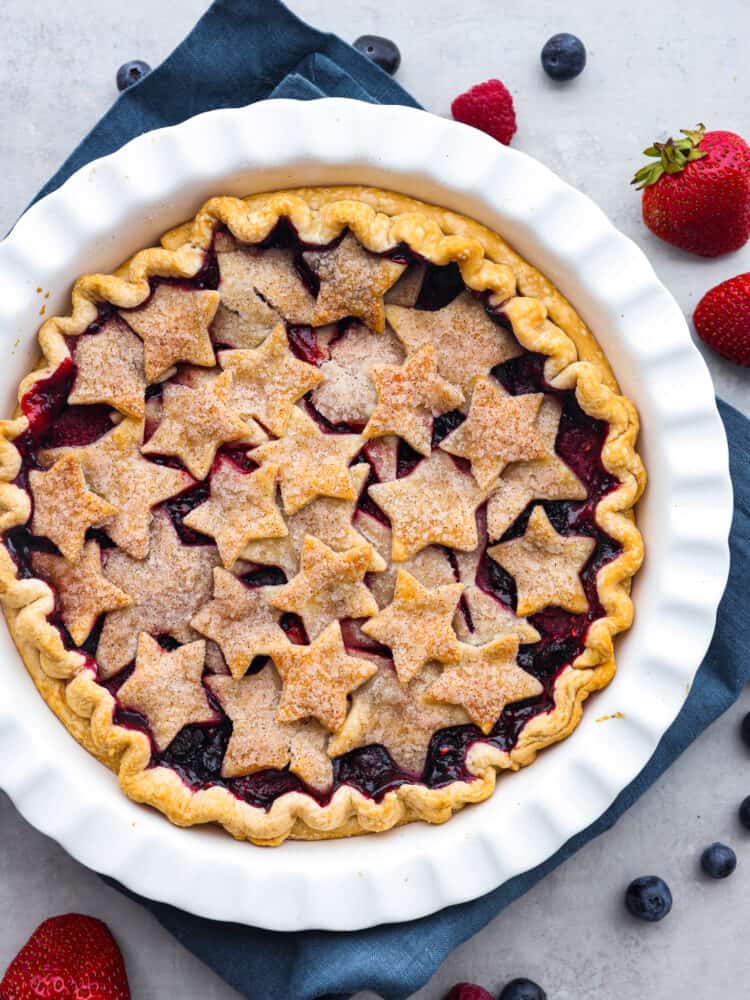 A patriotic fourth-of-July triple berry pie made simple with easy ingredients! This berry pie is bursting with juicy flavor and almost looks too good to eat. It's the perfect centerpiece for any summer celebration! Top-down view of a triple berry pie in a white serving dish.