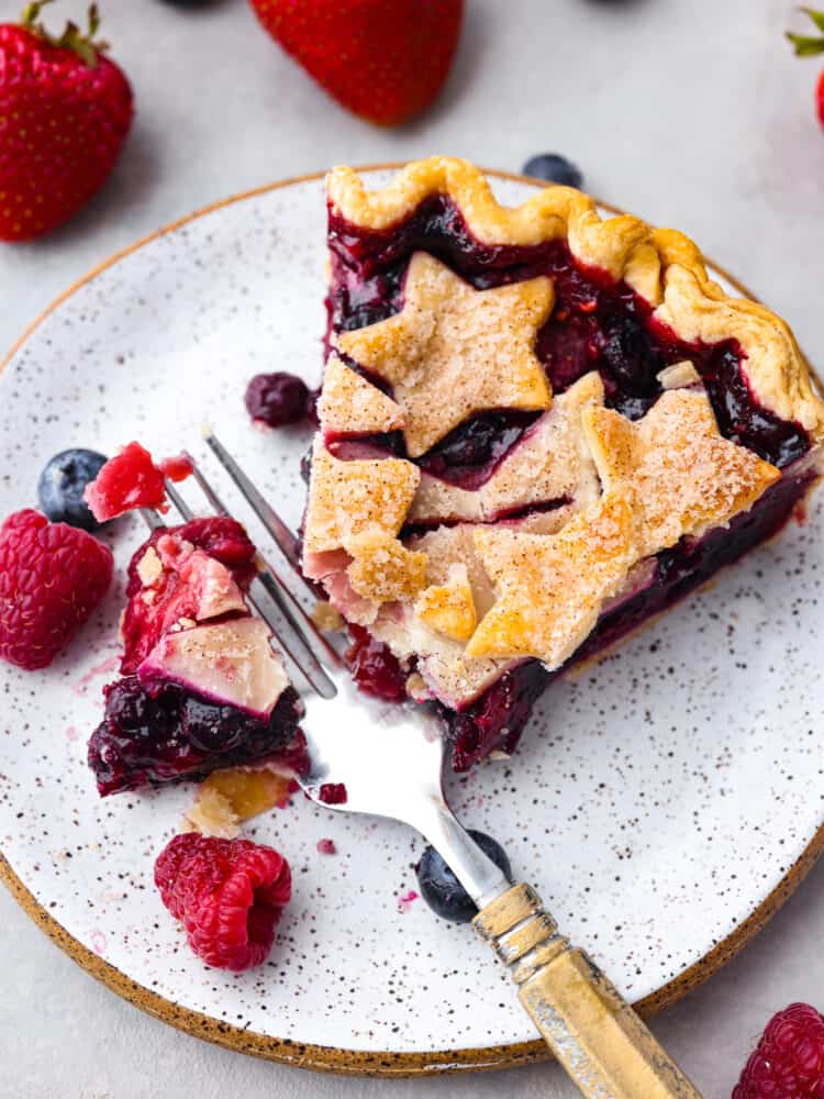 A patriotic fourth-of-July triple berry pie made simple with easy ingredients! This berry pie is bursting with juicy flavor and almost looks too good to eat. It's the perfect centerpiece for any summer celebration! Closeup of a slice of pie with a bite taken out of it.
