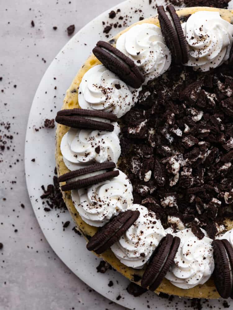 Let your teeth sink into the most delectable, creamy oreo cheesecake that you have ever had! Silky and smooth with the perfect bite-sized oreo bits in every single slice, you won't be able to stop raving about this cheesecake! The top view of half of an oreo cheesecake on a platter.